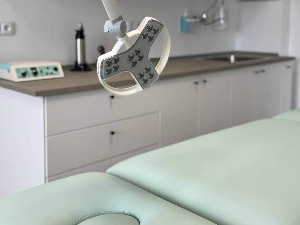 Vyšetřovací lůžko a vyšetřovací lampa v ambulanci MedDerm.